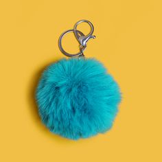 a blue furry ball keychain on a yellow background