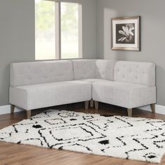 a living room with a white rug on the floor and a gray couch in front of it