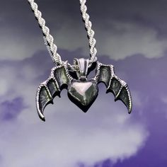 "A spooky silver necklace featuring a flying heart with bat wings charm on a 3mm rope chain. Safe in the shower, beach and pool! Our chains are 100% stainless steel and hypoallergenic so they won't rust, tarnish, or turn your neck green. - Water resistant - Lobster clasp closure - Will not rust or tarnish - Adjustable from 18\"-20\" - Stainless steel chain + pendant" Nickel-free Stainless Steel Heart Pendant Jewelry, Symbolic Heart Shaped White Gold Jewelry, Mystical Clavicle Chain Jewelry As Gift, Mystical Clavicle Chain Jewelry For Gift, Silver Celestial Jewelry Tarnish Resistant, Celestial Silver Jewelry Tarnish Resistant, Celestial Style Silver Tarnish-resistant Jewelry, Personalized Silver Celestial Jewelry, Spiritual Stainless Steel Pendant Jewelry