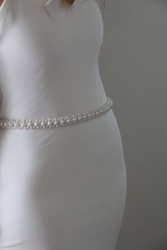 a woman in a white dress wearing a pearl belt