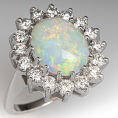 an opalite and diamond ring on a white background with the center stone surrounded by small diamonds