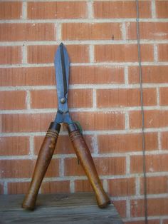 a pair of scissors sitting on top of a wooden table next to a brick wall