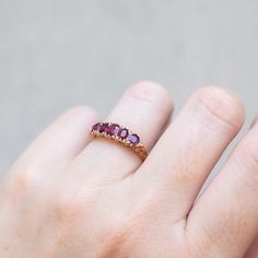 Cool magenta rubies are set in swirling filigree in this antique gold ring. The cushion shape of the stones pop from the carved band and tiny diamonds bookend each end. Originating from England in 1890, this bold ring is one of a kind. Stones: Five Rubies, Total 1.50tcw, Small White DiamondsMetal: 18k Yellow GoldMeasurements: Setting length: 13.7mm, Setting width: 5.1mm, Setting height: 4.3mm, Band width: 2.3-1.8mmWeight: 3g Size 6.5 in stock Shipping and Delivery: IN STOCK items will ship within 2 business days Sizes not In Stock will be Resized Resize Fee may apply Please allow 2 weeks for delivery All Resize items are final sale Please make sure to have your correct ring size before ordering Prices may vary by variant Antique Gold Ring, Antique Gold Rings, Deep Magenta, Bold Rings, Tiny Diamond, Antique Vintage Jewelry, 18k Yellow Gold Ring, Yellow Gold Ring, Hoop Ring