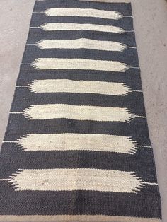 a black and white striped rug on the floor next to a wall with a sign that reads goundarts rug