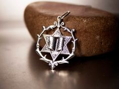 a silver pendant with an inverted design on it's side sitting on top of a rock