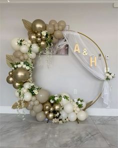 a white and gold balloon arch with flowers, greenery and balloons in the shape of a circle