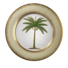 a white and gold plate with a palm tree painted on the side in an oval frame