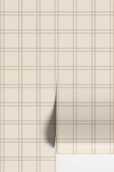 a beige plaid wallpaper with a white strip on the bottom right corner and an empty piece of paper in front of it