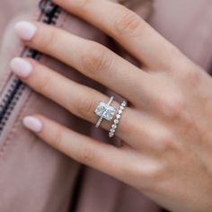 a woman's hand with a diamond ring on her finger and a pink jacket