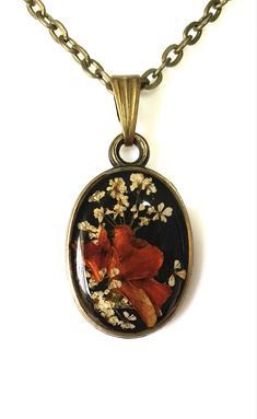 a necklace with flowers and leaves in the center on a chain that is attached to a white background