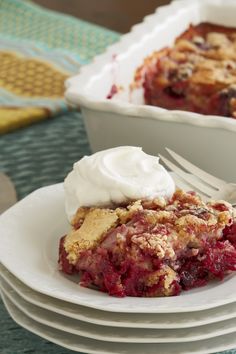 a slice of berry cobbler on a plate with a fork next to the pie