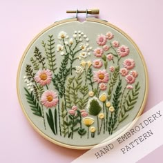 a hand embroidery pattern with pink and yellow daisies on a light green circle frame