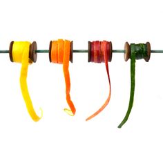 four spools of colored thread hanging from a clothes line with wooden pegs