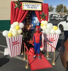 a spider man is standing in front of some popcorn boxes with balloons and stars on them