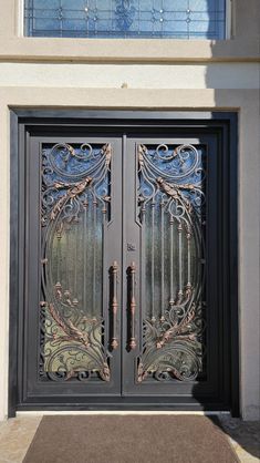 an ornate iron door is shown in front of a house with glass panels on the doors