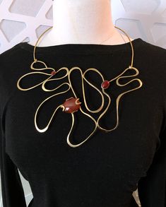 A bold contemporary sculpture to wear. This statement necklace is made for the person who likes to stand out in a crowd. It is a unique piece that you’ll reach for every time you want to be noticed. Hand-shaped and hammered brass wire with three carnelian stones. It has been lacquered to slow oxidation. The centerpiece is 81/2 inches across by 5 inches tall. It closes with hook and eye. It is 20 inches long and is shown on a size 12 dress form. Brass Jewelry Design, Hammered Metal Jewelry, Aluminum Wire Jewelry, Contemporary Jewellery Necklace, Metal Art Jewelry, African Beads Necklace, Contemporary Jewelry Design, Earring Trends, Hammered Brass