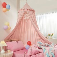 a pink canopy bed with balloons hanging from the ceiling