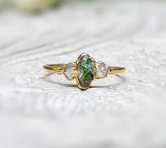 three stone ring sitting on top of a piece of white wood with green and yellow accents