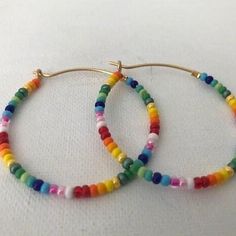 Colorful glass rainbow beads adorn a gold hoop earring. These lightweight earrings are so versatile. Vibrant Rainbow Jewelry With Colorful Design, Everyday Rainbow Round Bead Jewelry, Everyday Rainbow Jewelry With Round Beads, Trendy Colorful Beaded Hoop Earrings For Gifts, Everyday Rainbow Beaded Jewelry, Rainbow Colorful Beads Hoop Earrings, Rainbow Round Earrings With Colorful Beads, Rainbow Beaded Dangle Hoop Earrings, Rainbow Hoop Earrings With Colorful Beads