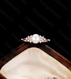 a pearl and diamond ring in a wooden box