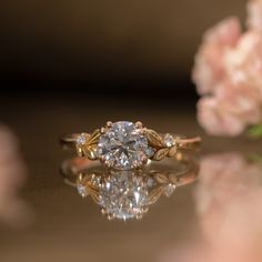 a diamond ring sitting on top of a table next to flowers