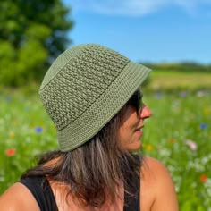 a woman with long hair wearing a green knitted hat in a flowery field