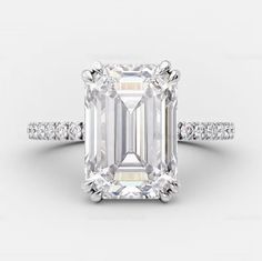 an emerald cut diamond ring with diamonds on the band and side stones in white gold