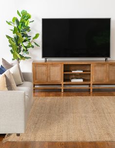 a flat screen tv sitting on top of a wooden entertainment center next to a couch