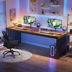 two computer monitors sitting on top of a wooden desk in front of a blue light