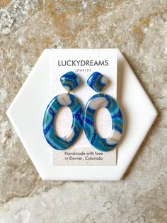 a pair of blue and white earrings sitting on top of a marble counter next to a sign