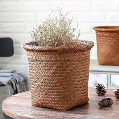 two woven baskets sitting on top of a wooden table next to pinecone cones