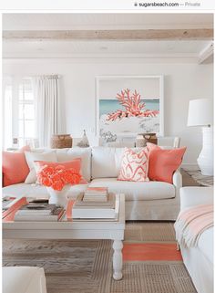 a living room filled with white furniture and orange pillows