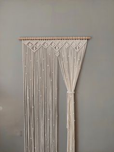 a macrame wall hanging on the side of a wall next to a window