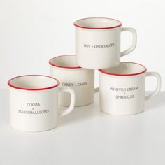 four coffee mugs sitting next to each other on a white counter top with red trim