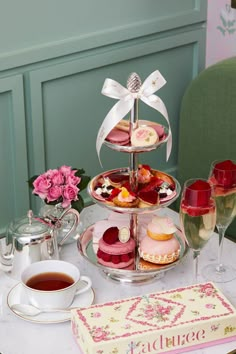 a table topped with three tiered trays filled with desserts and tea cups