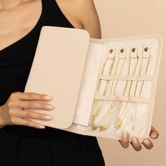 a woman holding an open case filled with jewelry