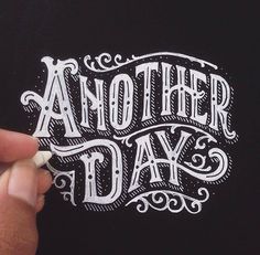 someone is writing another day on the back of a t - shirt with white ink