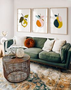 a living room with a green couch and rugs on the floor, framed pictures above it