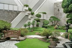 a japanese garden with green grass, rocks and trees in the center is an outdoor stair case