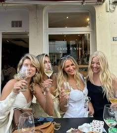 three beautiful women standing next to each other with wine glasses in front of their faces