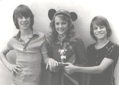 three women standing next to each other in front of a wall with mickey mouse ears on it