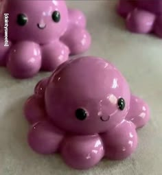 small pink octopus figurines sitting on top of a white surface with black eyes