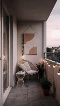 a white chair sitting on top of a balcony next to a potted plant and painting