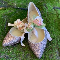 a pair of shoes with flowers on them sitting in the grass next to some moss