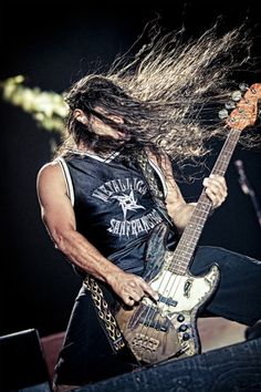 a man with long hair playing an electric guitar