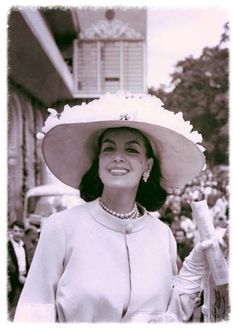 a black and white photo of a woman wearing a large hat