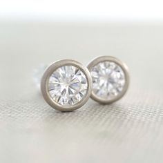 4 mm moissanite stud earrings, bezel set in 14k yellow, rose or white gold, or sterling silver. 14k white gold is pictured except for 6th photo which shows sterling silver. These earrings are made to order and will ship within 3-5 days. DETAILS - 4 mm moissanite - bezel setting - satin finish - solid 14k gold or sterling silver - white gold contains nickel, not rhodium plated - sold sterling silver or 14k gold backs - made to order within 3-5 days What is Moissanite? Moissanite is lab created si Classic Everyday Jewelry With Tension Setting, Timeless Round Earrings With Bezel Setting, Classic Earrings With Bezel Setting, Anniversary Diamond Earrings With Tension Setting, Fine Jewelry Round Diamond Earrings With Tension Setting, Fine Jewelry Diamond Earrings With Tension Setting, Everyday Sterling Silver Diamond Earrings With Round Cut, Classic White Jewelry With Bezel Setting, Hypoallergenic Classic Round Diamond Earrings