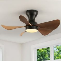 a ceiling fan with three wooden blades in a white room next to two windows and a window sill