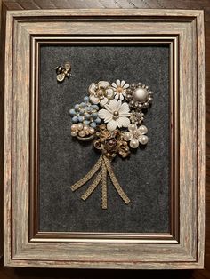 a bouquet of flowers in a frame with pearls and brooches on the side