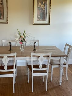 a dining room table with four chairs and a vase filled with flowers on top of it